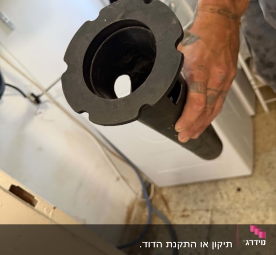 יד מחזיקה צינור שחור בחדר שירות